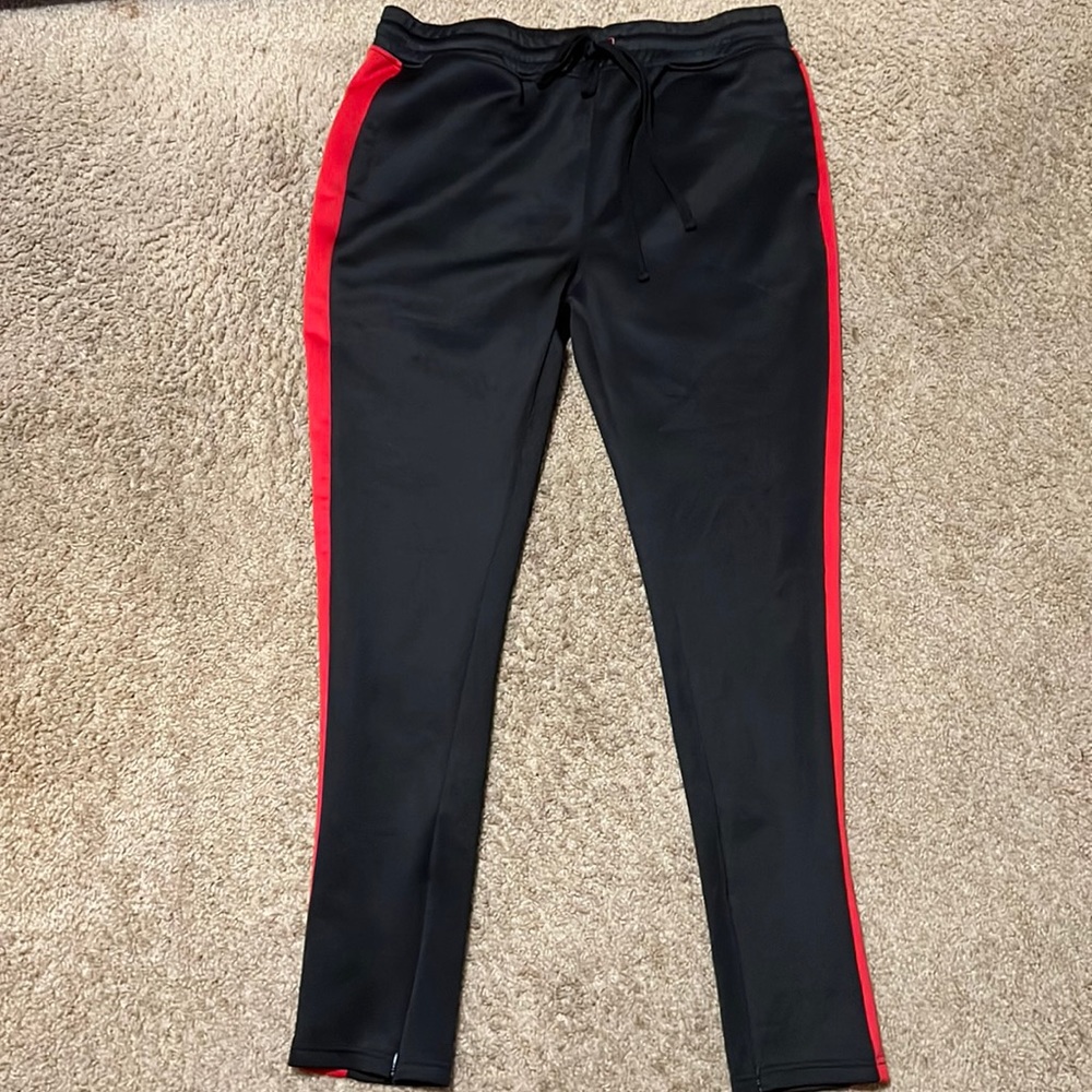 Black jogging pants w/ red stripe down the side. Zipper on the side of leg